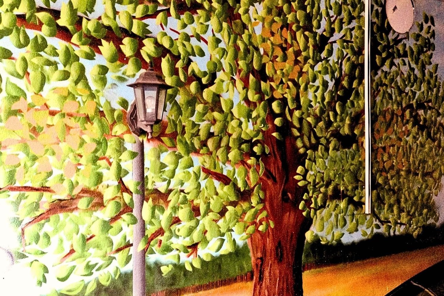 Graffiti-Wandbild mit Baum, Blättern und Laterne in fotorealistischer Ausführung