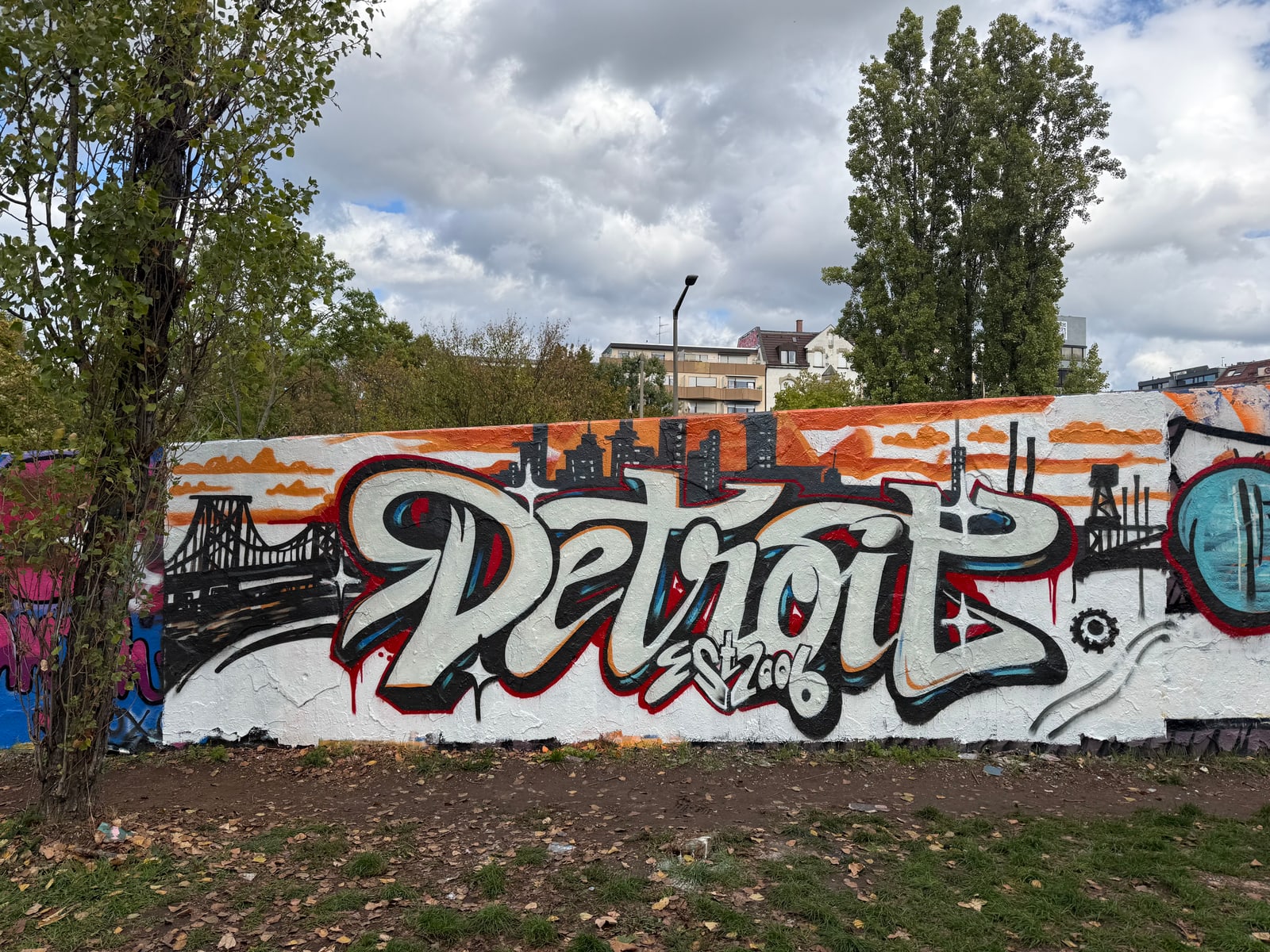 Die fertige Detroit-Wand seitlich von der Wiese aus, mit Brücke, Skyline und Zahnrad im Motiv.