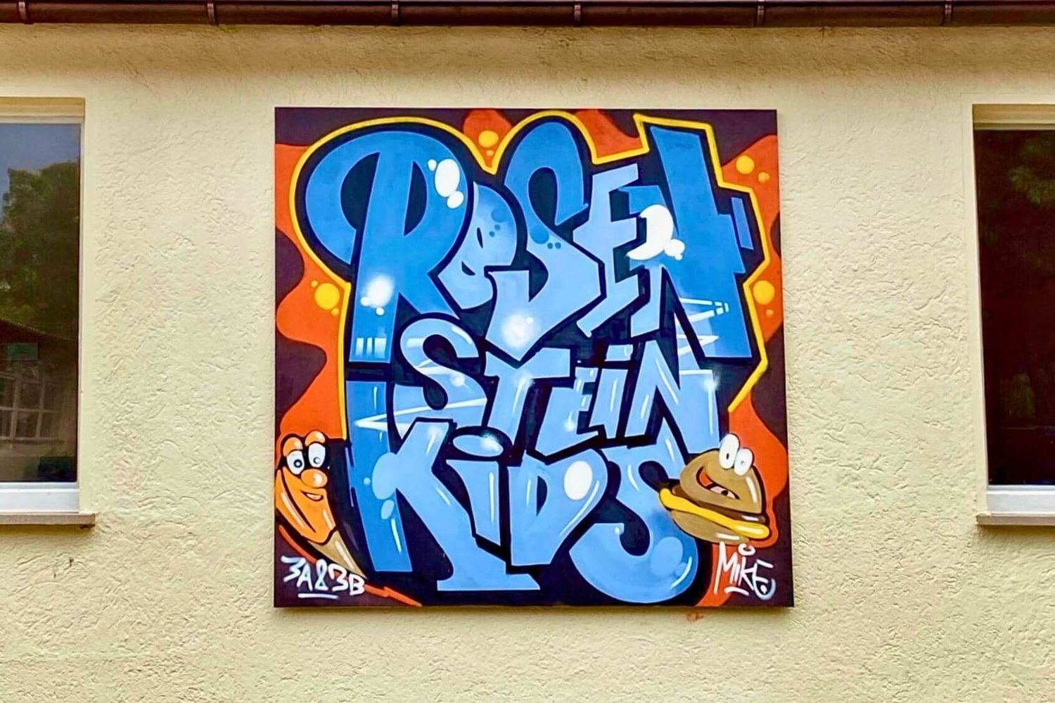Bunte, von Schulkindern gestaltete Graffiti-Holzplatten an der Außenwand der Rosensteinschule am Nordbahnhof Stuttgart Nord, professionell mit Feinschliff von Graffiti Coach Open Mike.