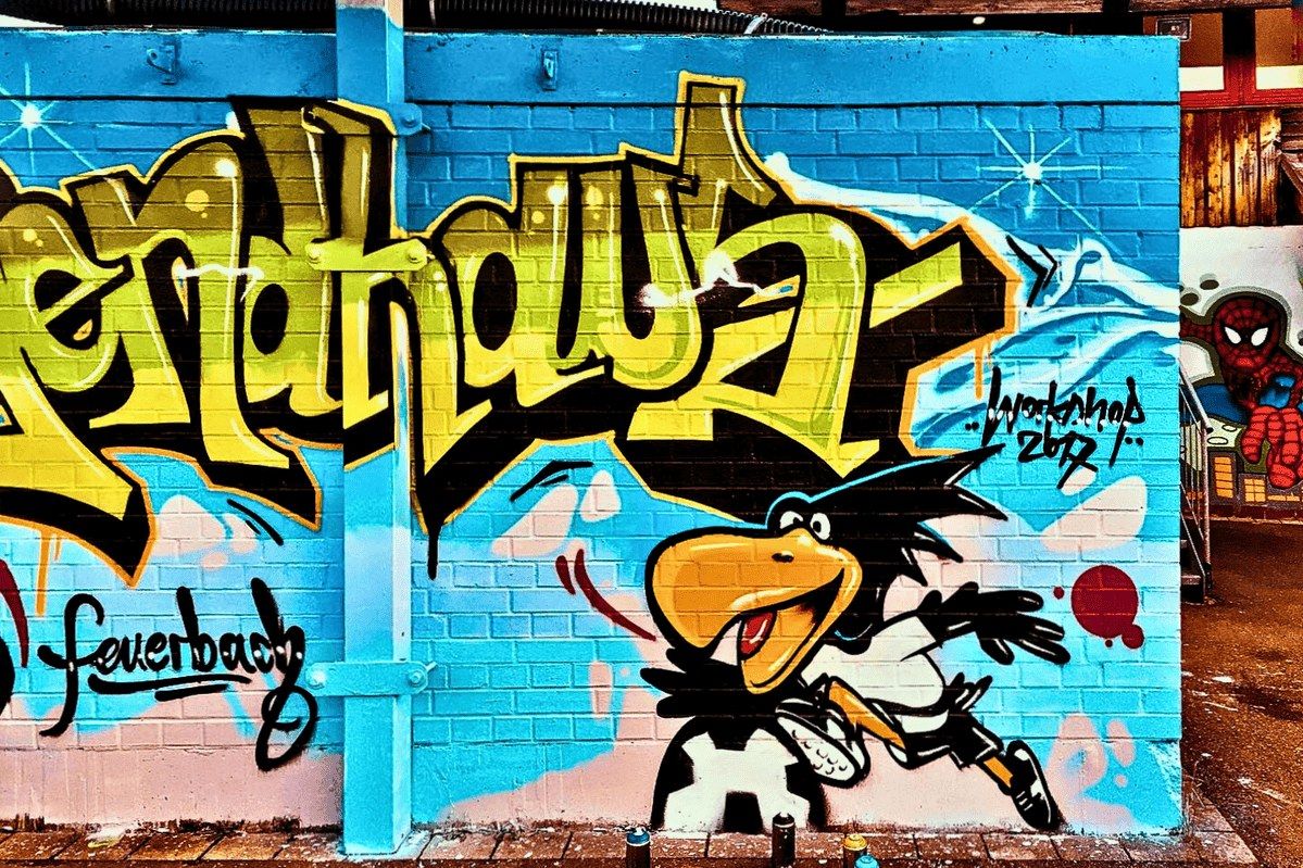 Detail des Graffiti Schriftzugs „Jugendhaus“ mit figürlichen Motiven aus dem Urban Art Workshop im Innenhof des Jugendhauses Feuerbach