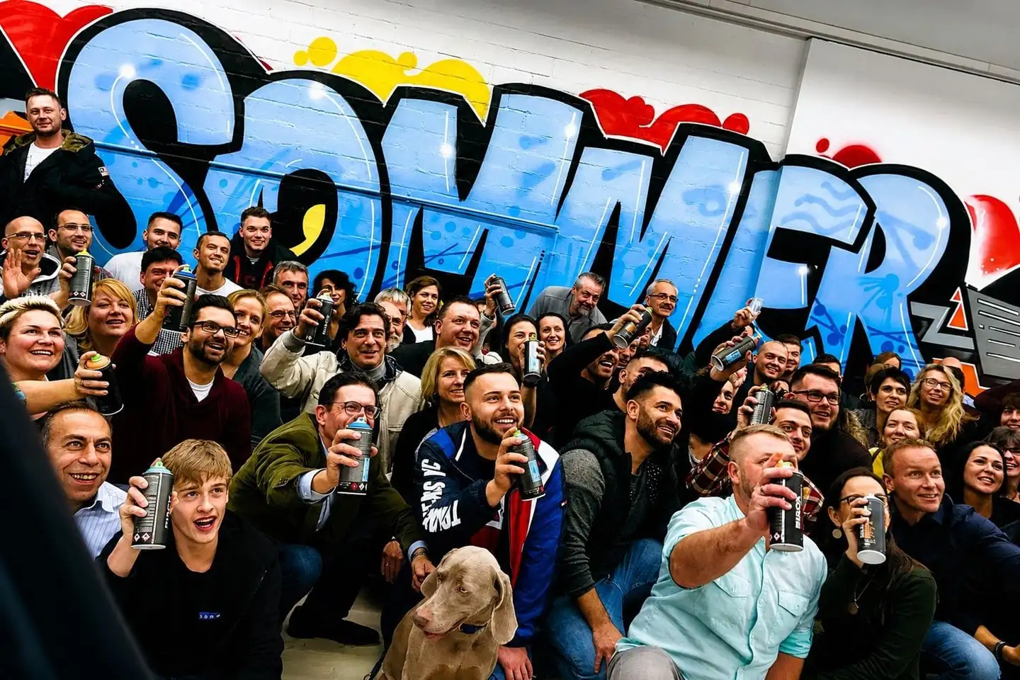 Graffiti-Teamevent in Stuttgart — Gruppe mit Spraydosen vor einem bunten Mural von Open Mike