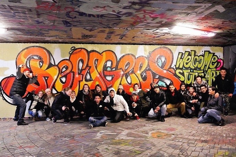 Gruppe beim gemeinsamen Sprühen im Graffiti-Workshop