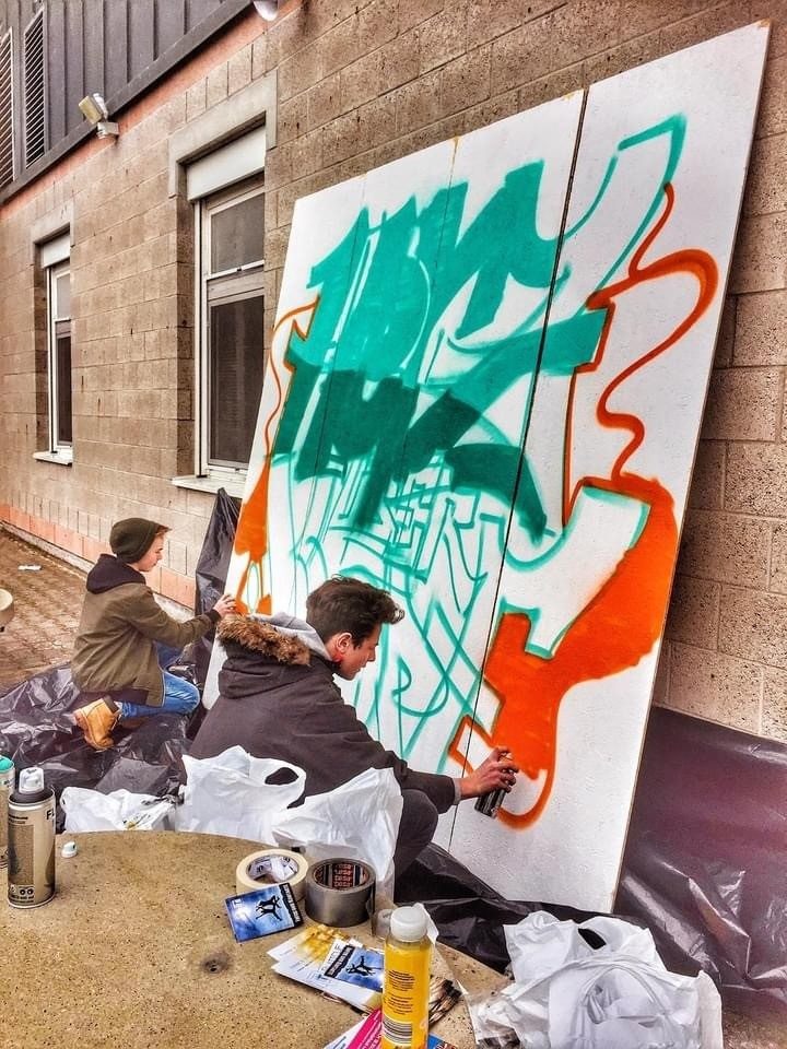 Teilnehmer beim Besprühen einer Leinwand im Graffiti-Workshop