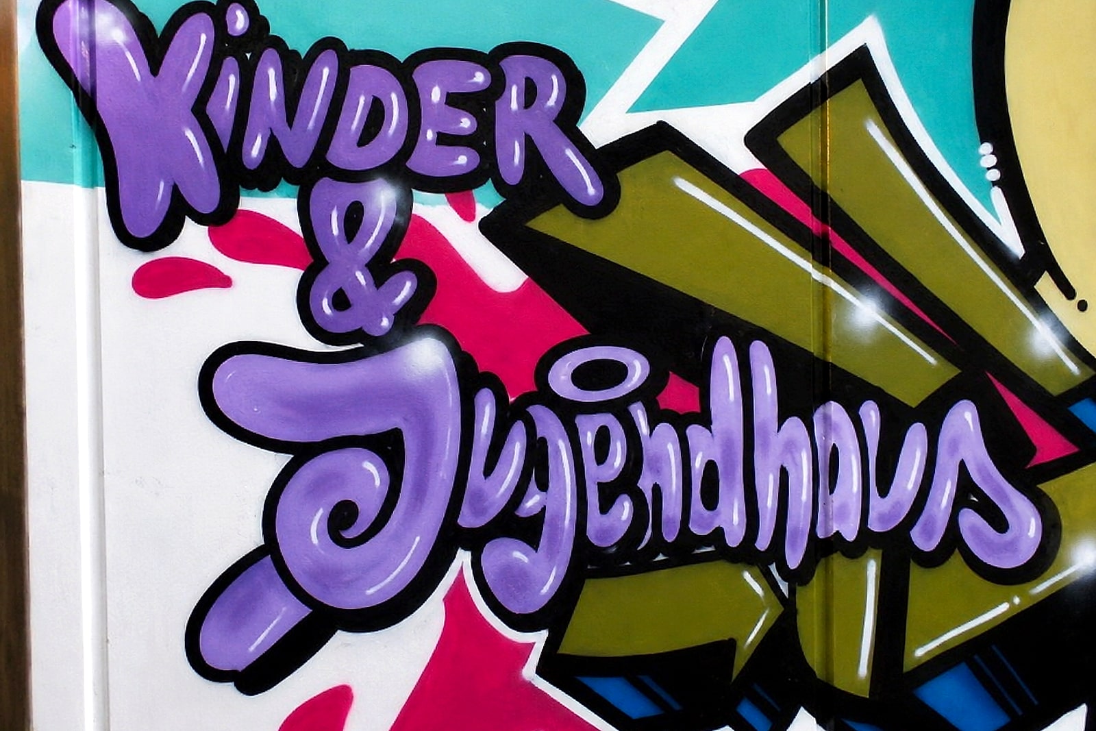 Detail: der Schriftzug »Kinder & Jugendhaus« in lila Bubble-Buchstaben an der Fassade in Stuttgart-Hausen.