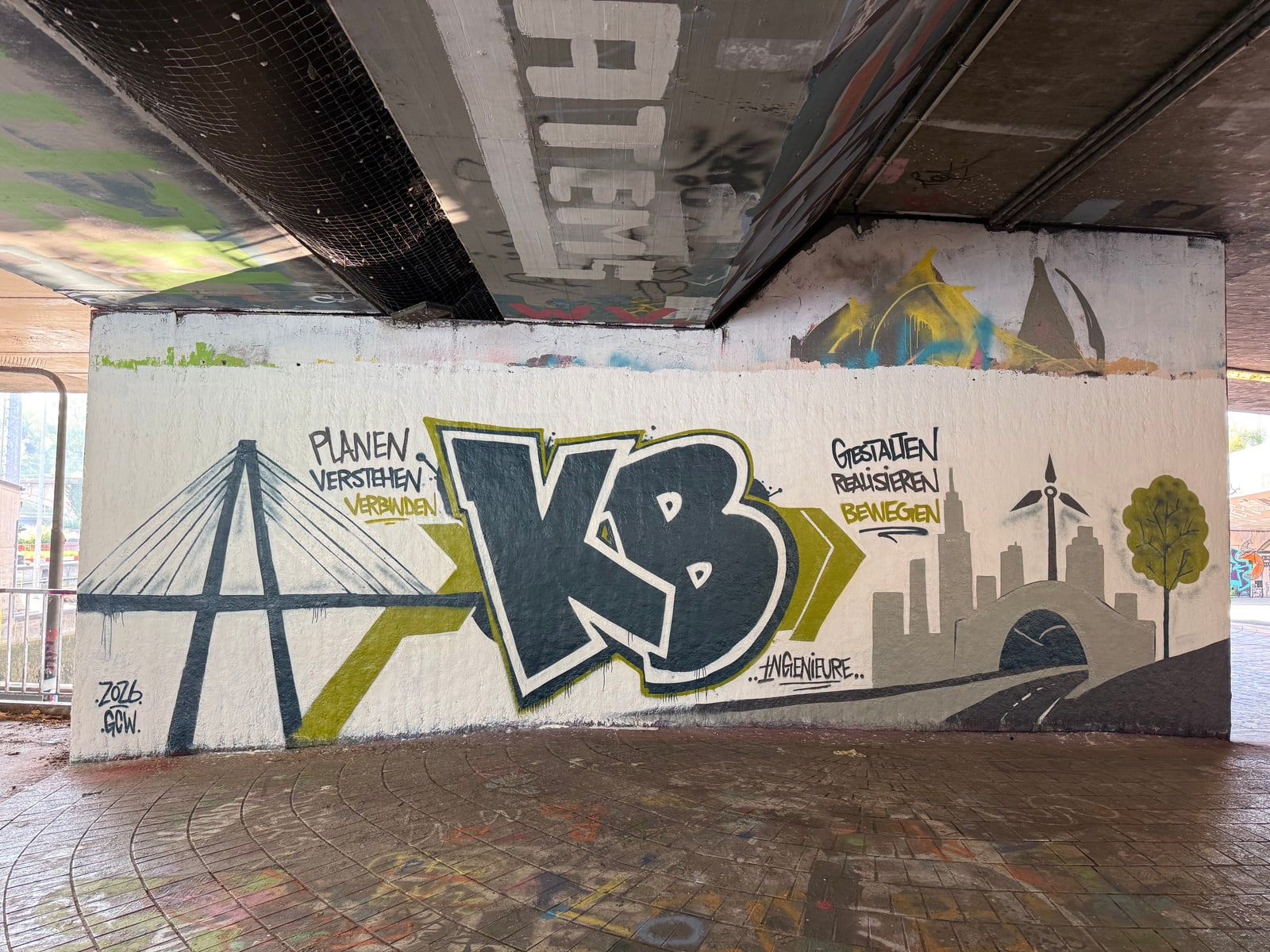 Fertiges Wandbild: dunkelblauer KB-Schriftzug, Schrägseilbrücke, Windrad, Skyline, Baum, Texte »Planen Verstehen Verbinden« und »Gestalten Realisieren Bewegen«.