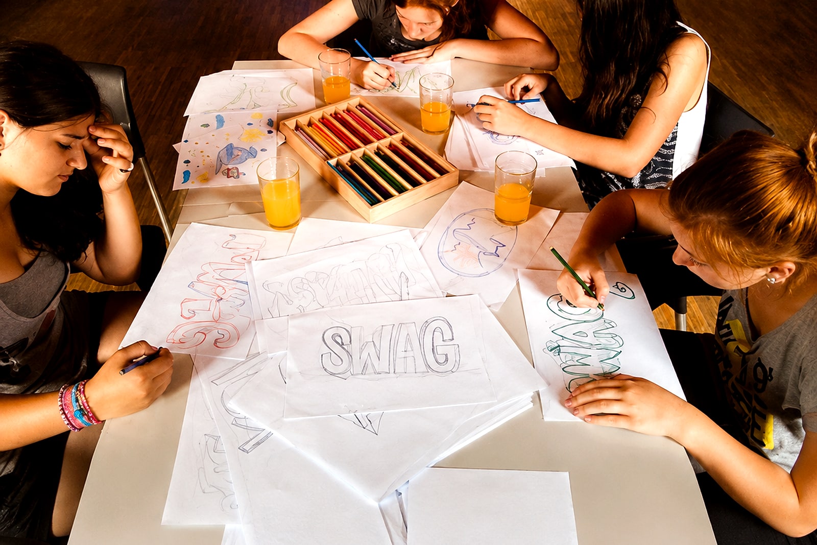Jugendliche zeichnen am Tisch mit Buntstiften Graffiti-Skizzen zum Wort »swag« im Jugendhaus Künzelsau