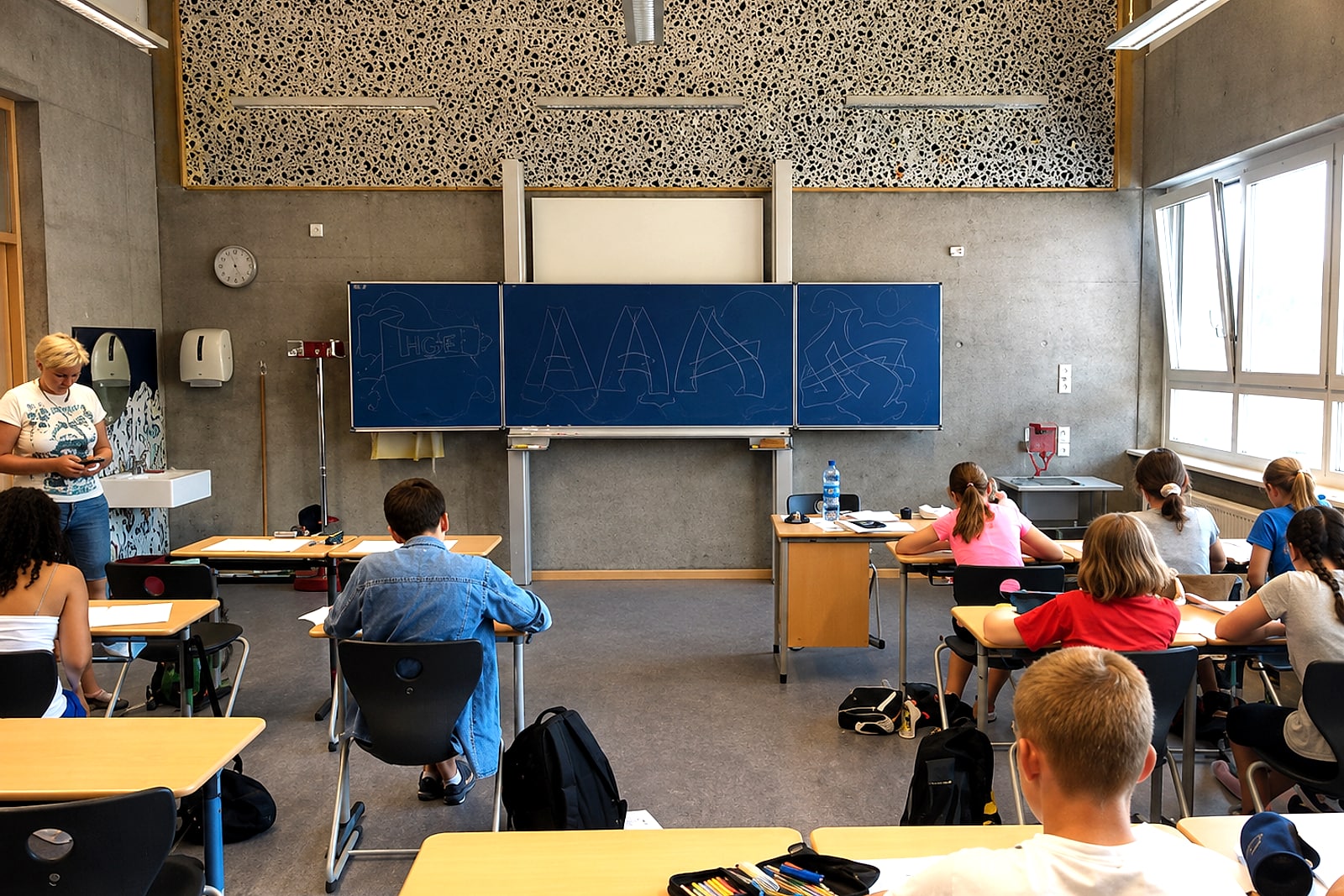 Schüler:innen zeichnen im Klassenraum der Reuchlin-Realschule Graffiti-Buchstaben, an der Tafel erste Skizzen