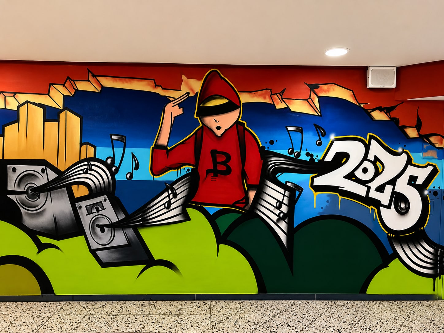 Wandbild: Figur mit rotem Kapuzenpulli und B-Logo, Lautsprecher, Notenbänder, Schriftzug 2025, grüne Hügel, blauer Himmel