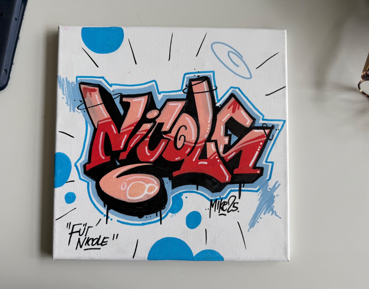 Leinwand mit dem Namen »Nicole« in rot-schwarzen Graffiti-Buchstaben mit blauem Umriss, signiert »Mike 25«