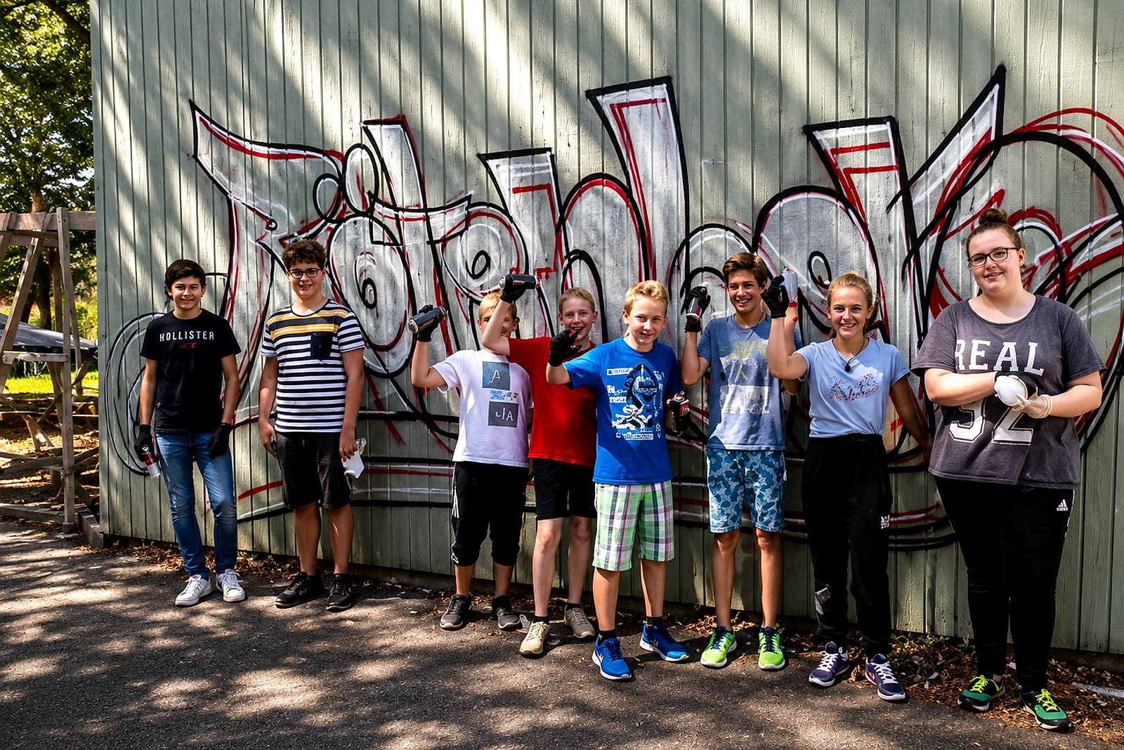 Gruppe Jugendlicher vor ihrem selbst gestalteten Graffiti-Piece am Treffpunkt Rötenberg in Aalen.