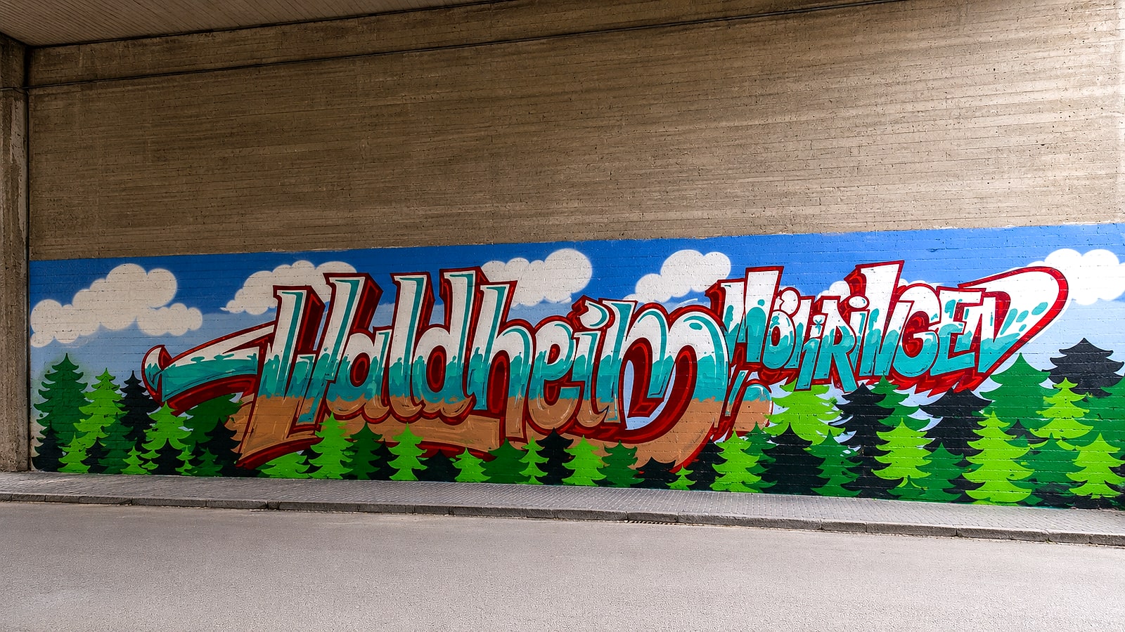 Großes Graffiti-Mural »Waldheim Möhringen« mit Tannenwald und Wolken auf einer Unterführungswand, gestaltet im Ferienwaldheim Stuttgart-Möhringen.