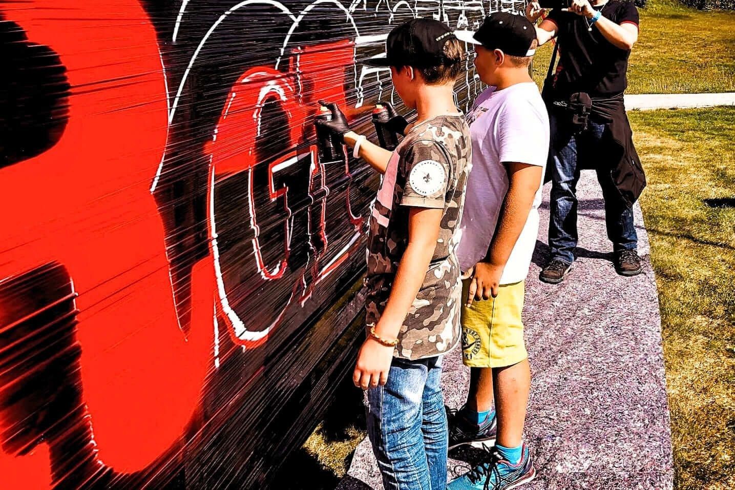 Festivalbesucher:innen beim Sprayen auf die Filmleinwand im Graffiti-Workshop mit Open Mike beim Rothaus Food Festival.